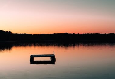 a boat floating on top of a lake at sunset