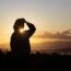 A man standing on top of a hill looking at the sun