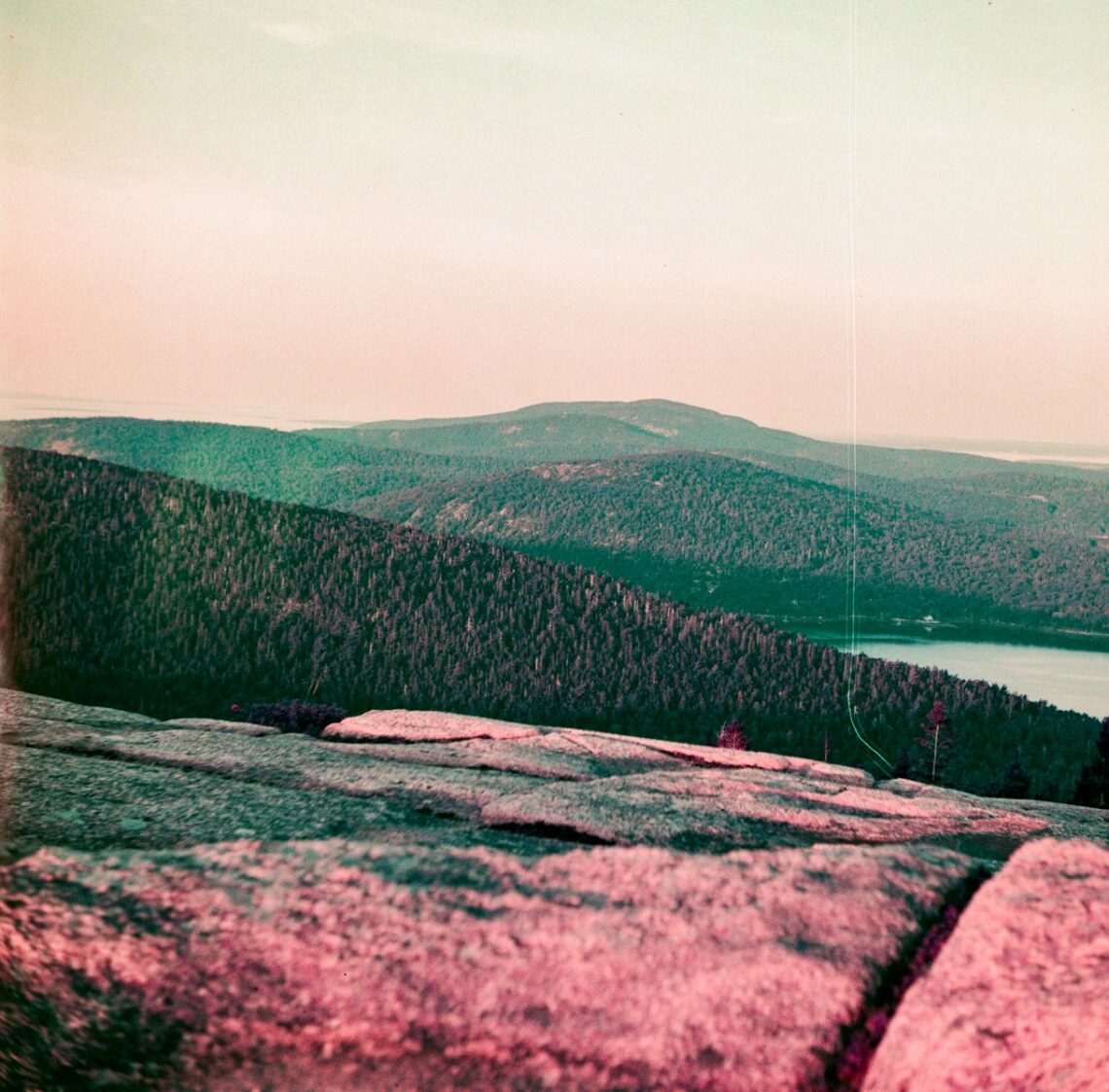 A man standing on top of a mountain next to a lake