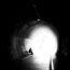 A person sitting in the middle of a dark tunnel